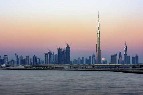 Moon passing behind the iconic Burj Khalifa at sunset. The light started to enlightened the top of the tower., United Arab Emirates, Middle East, Arabian Peninsula